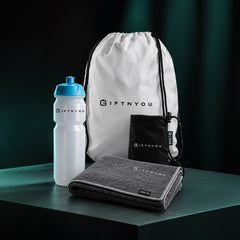 The Team Fitness Essentials Kit by GiftNYou with white sports bottle with blue cap, grey sports towel, black drawstring storage pouch in a fitness setting