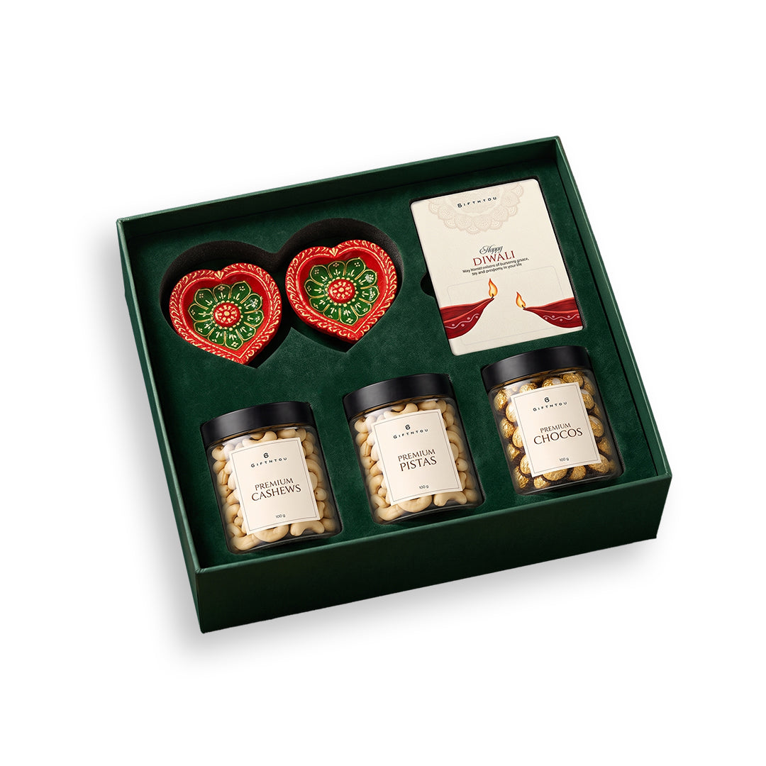 GiftNYou Diwali gift box with cashews, pistachios, chocolates, two heart-shaped diyas and a greeting card on white