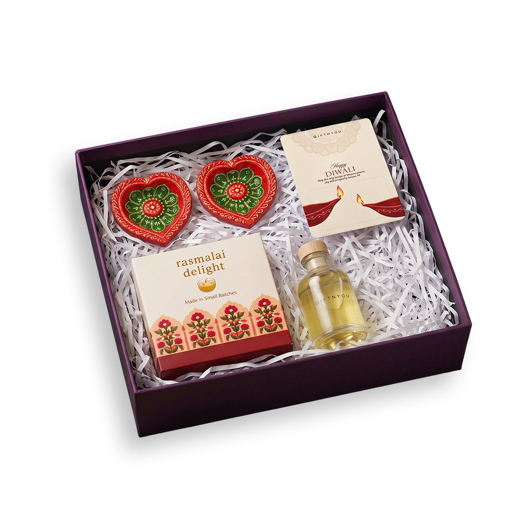 GiftNYou Diwali gift box with Rasmalai Delight candle, two diyas, stoppered bottle and greeting card on white