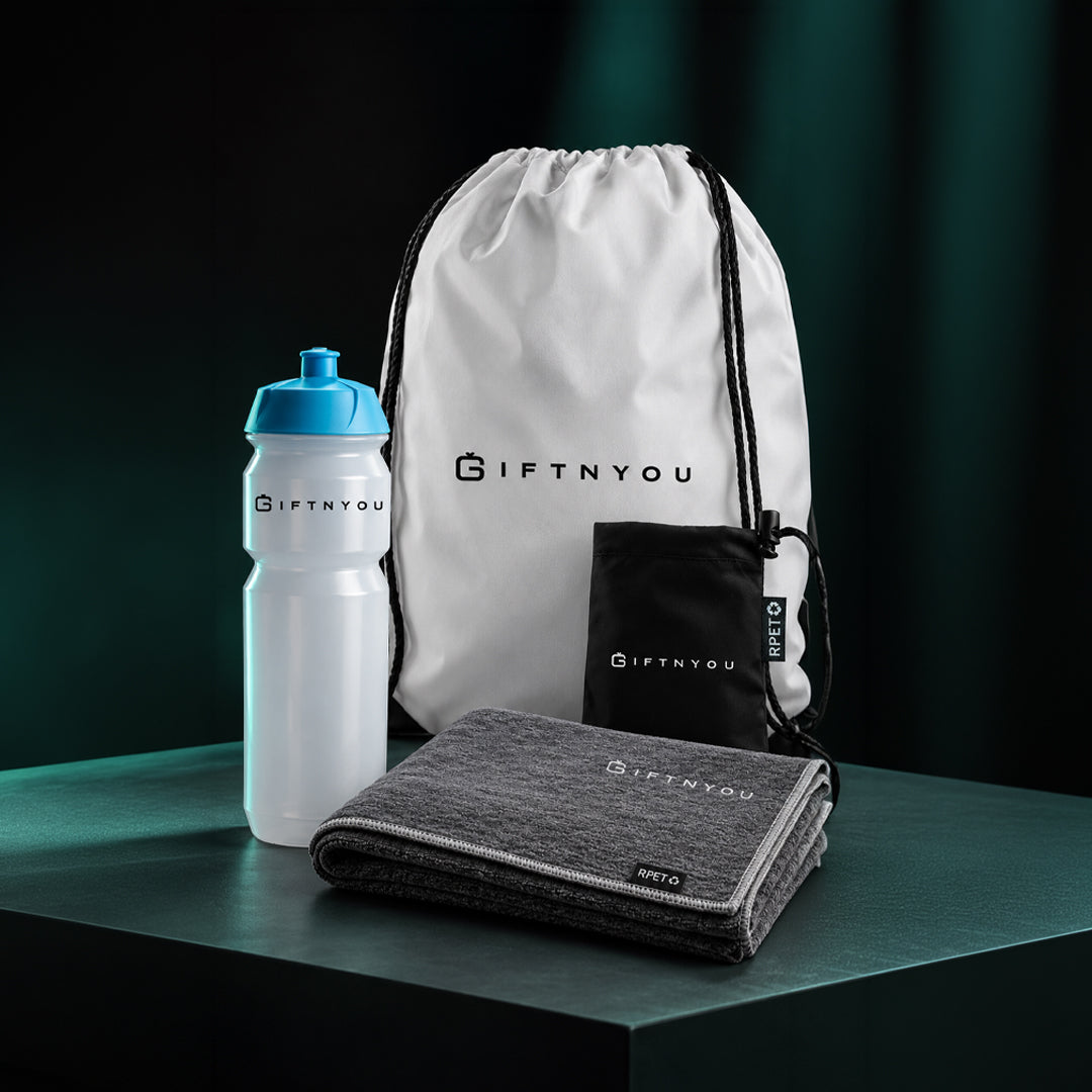 The Team Fitness Essentials Kit by GiftNYou with white sports bottle with blue cap, grey sports towel, black drawstring storage pouch in a fitness setting